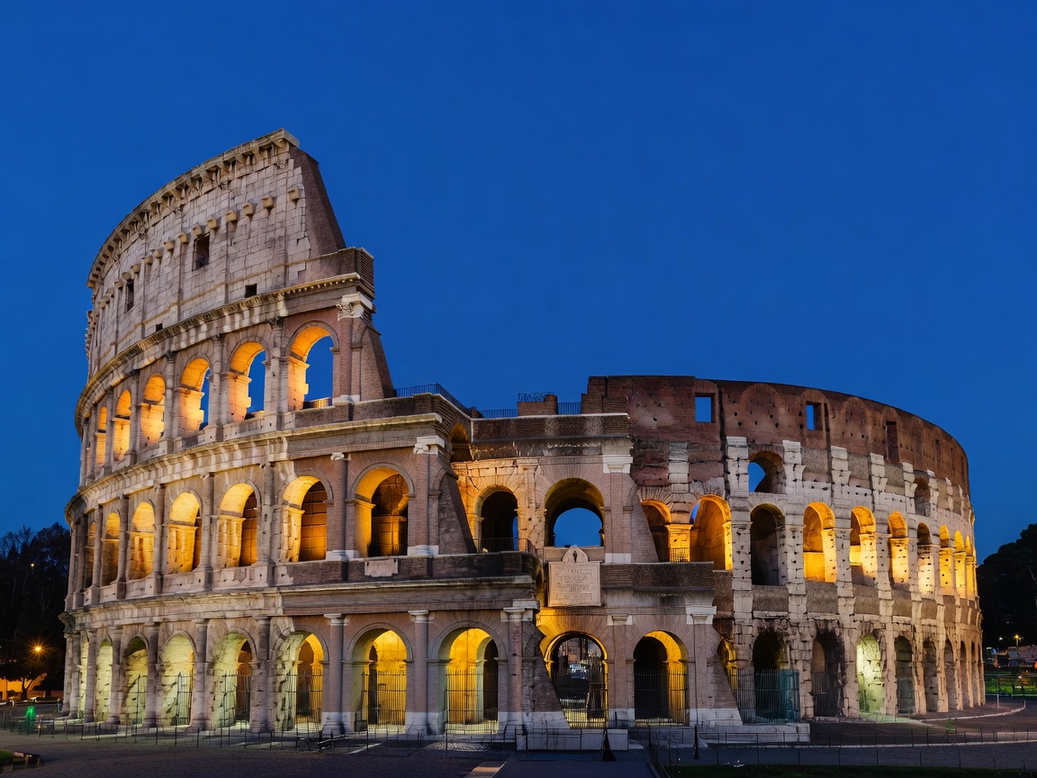 The Roman Colosseum illuminated during blue hour evening in Rome Italy